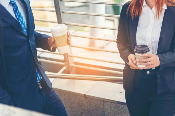 Businessman Businesswoman drink coffee in town outside office modern city. Hands holding take away coffee cup talking together happy fun. Partner Business people formal suit with cup of coffee