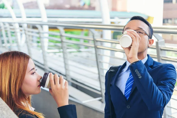 Businessman Businesswoman drink coffee in town outside office modern city. Hands holding take away coffee cup talking together happy fun. Partner Business people formal suit with cup of coffee