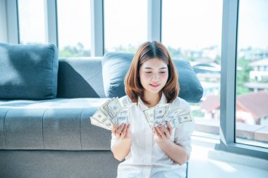 Elinde dolar olan mutlu Asyalı kadın mutluluğu kutluyor zenginliği kutluyor piyango parası yağmur damlası. Kazanan iş kadını para akışı yapar gülen surat