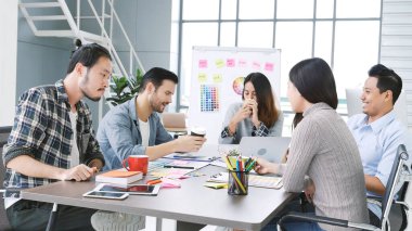 Çok ırklı iş adamlarından oluşan bir grup konferans salonunda iş dünyası grafiği ve grafiği üzerinde fikir alışverişinde bulunuyor. Çok Kültürlü Takım Çalışması, iş ortakları ve güven ortakları bir araya gelecek.