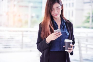 İş kadını internet üzerinden akıllı telefon alışverişi yapıyor, arıyor, internet teknolojisi yaşam tarzı mesaj yolluyor. Şehir caddesinde cep telefonu kullanan Asyalı kadın. Akıllı telefon akıllı, kendine güvenen kadın modern şehir.