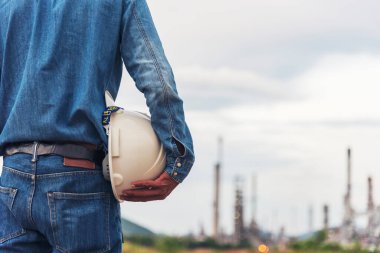 İnşaat mühendisi elleri inşaat mühendisliği için beyaz kaskı tutuyor. İnşaat mühendisi takım elbiseli adam inşaat sahasında beyaz kasklı kaskı elinde tutuyor.