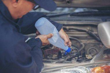 Araba tamircisi elleri araba aküsü mekanik servisi için arıtılmış arıtılmış su döküyor. Kapatın elleri adamım. Deiyonize edilmiş sıvı su şişesini garajdaki mobil araba servisinde tutun.