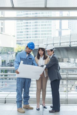 İnşaat mühendisi takımları modern kentteki inşaat sahasında birlikte çalışan işçi kaskı takıyorlar. Foreman Endüstri Mühendislik Mühendisliği ekip çalışması. Asya endüstrisi profesyonel takımı