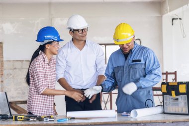 İnşaat mühendisi takım çalışması güvenlik ekibi, inşaat sahasında beyaz sarı şapkalı güvenlik ekipmanı tutuyor. Hardhat İnşaat Mühendisliği Mühendisliği Yöneticisini Koru