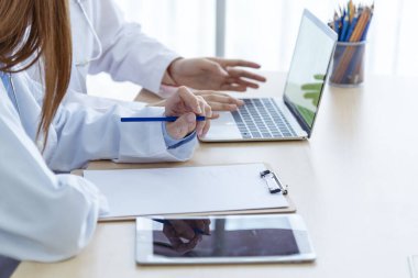 İki Asyalı kadın doktor dizüstü bilgisayarlı hasta danışmanlığı kullanarak doktorun muayenehanesiyle görüşmeyi tartışıyor. Asya tıp laboratuarındaki genç kadınlar birlikte sağlık hizmetleri ekip çalışmasını tartışıyorlar.