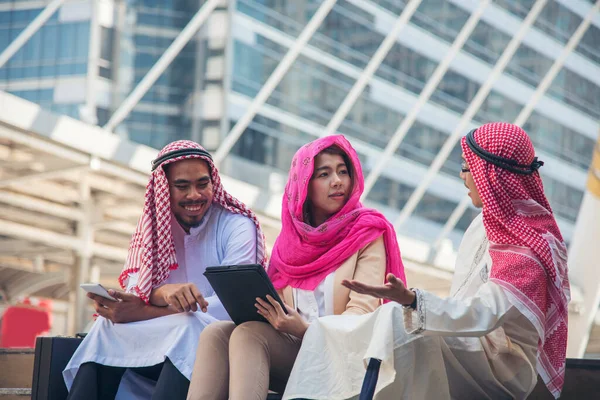 Dijital pazarlama grubu Arap insanlar modern müslüman BAE şehir dokunmatik ekran tartışmasında akıllı tablet kullanıyorlar. Girişimci Asyalı insanlar patronlarıyla dışarıda konuşurken gülümserler.