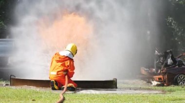 İtfaiyeci yangın hortumuyla, kimyasal köpüklü sprey motorla savaşıyor. İtfaiyeciler korunmak için kasketli, vücut korumalı üniformalı üniforma giyer. Yangın söndürücüde kurtarma eğitimi.