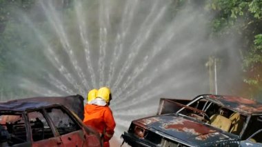 İtfaiyeci yangın hortumuyla, kimyasal köpüklü sprey motorla savaşıyor. İtfaiyeciler korunmak için kasketli, vücut korumalı üniformalı üniforma giyer. Yangın söndürücüde kurtarma eğitimi.
