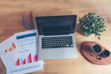 Ofis dizüstü bilgisayarının finansal döküman şeması ve kahve fincanı ile ahşap masanın üzerindeki grafiği. Düz dizüstü bilgisayar ofis masasında duruyordu. İş sahasında iş grafiği modellemesi yok