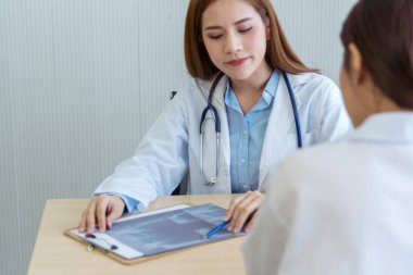 İki Asyalı kadın doktor, doktorun muayenehanesinde röntgen filmi danışmanlığı yapan hastalarla görüşmeyi tartışıyor. Asya tıp laboratuarındaki genç kadınlar birlikte sağlık hizmetleri hakkında konuşuyorlar.