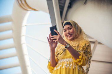 Akıllı telefon uygulaması kullanan İslami kadın, ajanda gündemini akıllı telefon Müslüman modern uae şehrine odaklıyor. Arap kadın tesettür ve Müslüman resmi elbisesi giyer çevrimiçi yaşam tarzı mesajları gönderir