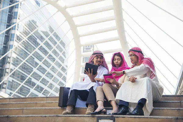 数字营销群体中的阿拉伯人使用智能平板电脑行走在现代穆斯林的阿联酋城市触摸屏讨论 亚洲企业家在户外与老板交谈时面带微笑 — 图库照片