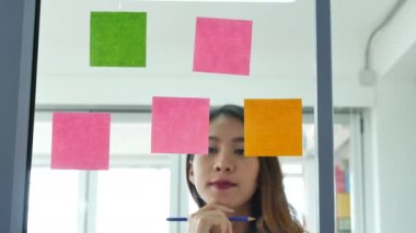 Yaratıcı tasarımcı kadın konuşuyor yapışkan notlar kullanıyor, fikirleri sunuyor. Çeşitli etnik gruplar, iş ortaklarıyla toplantı yapan ve konferans odasında fikirlerini paylaşan beyin fırtınası yapan gruplar.. 