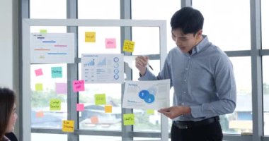 Mutlu iş adamları toplantı odasında grafik çizelgesi yatırımıyla ve iş verileriyle tanışıyor. Bir grup iş adamı konferans odasında toplanıyor. Asyalı iş adamı konuşması, mevcut takım çalışması ortaklığı