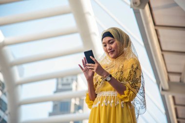 Akıllı telefon uygulaması kullanan İslami kadın, ajanda gündemini akıllı telefon Müslüman modern uae şehrine odaklıyor. Arap kadın tesettür ve Müslüman resmi elbisesi giyer çevrimiçi yaşam tarzı mesajları gönderir