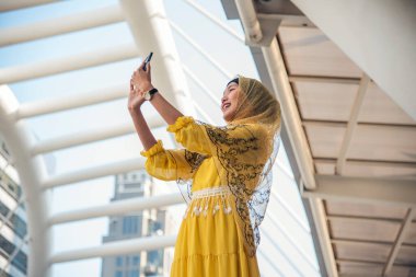 Akıllı telefon uygulaması kullanan İslami kadın, ajanda gündemini akıllı telefon Müslüman modern uae şehrine odaklıyor. Arap kadın tesettür ve Müslüman resmi elbisesi giyer çevrimiçi yaşam tarzı mesajları gönderir