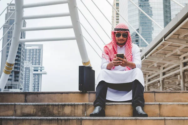 伊斯兰男子使用智能手机应用程序组织日程日程关注手握智能手机的穆斯林现代乌艾城市 阿拉伯男性穿着头巾和穆斯林的正式服装 发送短信 发送网上生活方式 — 图库照片