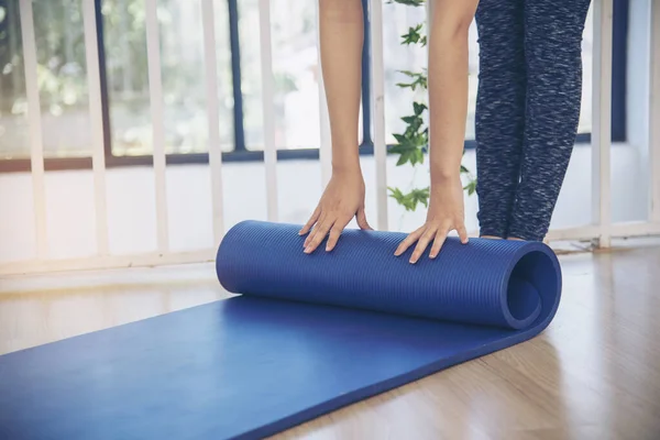 女子手在瑜伽练习室的健身房地板上卷起瑜伽垫 在家锻炼的女人紧紧抓住手卷泡沫瑜伽体操垫 妇女赤脚在家锻炼 健康生活方式概念 — 图库照片