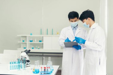İki Asyalı bilim adamı kimya bilimi tüpü deney tüpü antikor örneğini kovid-19 virüsüne karşı laboratuvar geliştirmek için depoluyorlar. Kimya Laboratuarı 'nda bilim adamı danışmanı, analizi