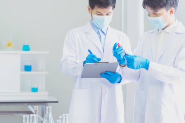 İki Asyalı bilim adamı kimya bilimi tüpü deney tüpü antikor örneğini kovid-19 virüsüne karşı laboratuvar geliştirmek için depoluyorlar. Kimya Laboratuarı 'nda bilim adamı danışmanı, analizi