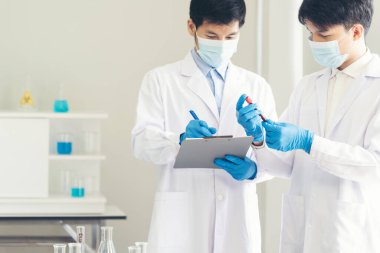 İki Asyalı bilim adamı kimya bilimi tüpü deney tüpü antikor örneğini kovid-19 virüsüne karşı laboratuvar geliştirmek için depoluyorlar. Kimya Laboratuarı 'nda bilim adamı danışmanı, analizi