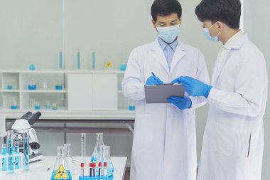 İki Asyalı bilim adamı kimya bilimi tüpü deney tüpü antikor örneğini kovid-19 virüsüne karşı laboratuvar geliştirmek için depoluyorlar. Kimya Laboratuarı 'nda bilim adamı danışmanı, analizi