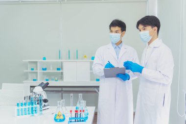 İki Asyalı bilim adamı kimya bilimi tüpü deney tüpü antikor örneğini kovid-19 virüsüne karşı laboratuvar geliştirmek için depoluyorlar. Kimya Laboratuarı 'nda bilim adamı danışmanı, analizi