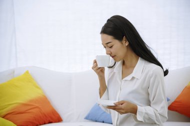 Ofiste işten sonra kahve fincanı tutan kadın kafede sıcak bir tat alıyor. Ofis masasında oturan, elinde kahve fincanı tutan, rahatlayan ve eğlenen bir kadının ellerini kapat. Sıcak kahve fincanı elimde.