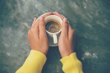 Ofis masasında oturan, elinde kahve fincanı tutan, rahatlayan ve eğlenen bir kadının ellerini kapat. Elinde sıcak kahve fincanı. Elinde kahve fincanı tutan kadın işten sonra kafede dinleniyor.