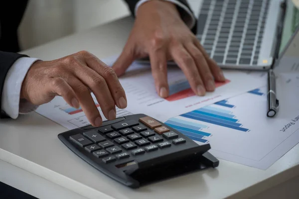 Close up Man hands calculating number, data, graph, chart audit planning accountancy on business report. Business man hands using calculator counting tax financial bill.  Tax audit Finacial concept.