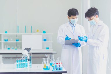 İki Asyalı bilim adamı kimya bilimi tüpü deney tüpü antikor örneğini kovid-19 virüsüne karşı laboratuvar geliştirmek için depoluyorlar. Kimya Laboratuarı 'nda bilim adamı danışmanı, analizi