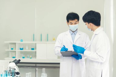 İki Asyalı bilim adamı kimya bilimi tüpü deney tüpü antikor örneğini kovid-19 virüsüne karşı laboratuvar geliştirmek için depoluyorlar. Kimya Laboratuarı 'nda bilim adamı danışmanı, analizi