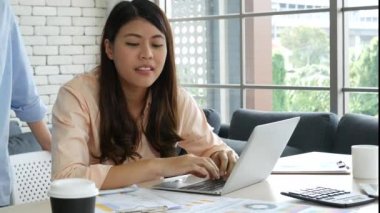 Ofis masasında kendine güvenen iki kadının birlikte çalışması mutluluktur. Bilgisayar şirketi ile çalışan takım ortakları. Asyalı iş arkadaşı arkadaşlığı gülen yüzle iş başında.