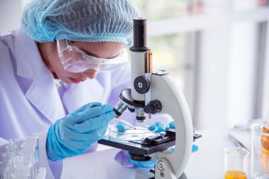 Laboratuvardaki kadın bilim adamı mikroskop tıbbi testine ve biyoloji kimyasına bakıyor. Bilimsel eczane genetik araştırmalarını analiz eden kadın teknisyen laboratuarı. Kimya Tıp Laboratuvarı