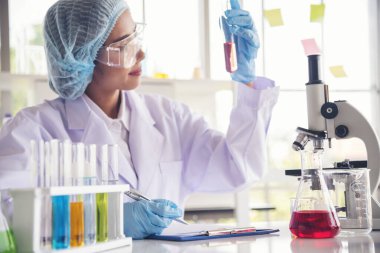 Kapalı alan kadın bilim adamı laboratuvarda düşürücü kullanıyor. Bilimsel mikroskop tıbbi testi, biyoloji kimyası araştırması. Kadın teknisyen laboratuarı kan bilimsel ilaç araştırmalarını inceliyor..