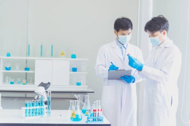 İki Asyalı bilim adamı kimya bilimi tüpü deney tüpü antikor örneğini kovid-19 virüsüne karşı laboratuvar geliştirmek için depoluyorlar. Kimya Laboratuarı 'nda bilim adamı danışmanı, analizi