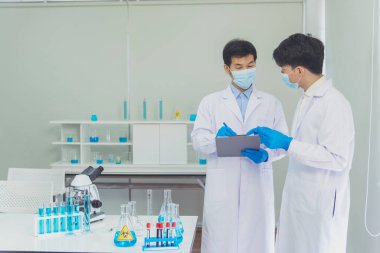 İki Asyalı bilim adamı kimya bilimi tüpü deney tüpü antikor örneğini kovid-19 virüsüne karşı laboratuvar geliştirmek için depoluyorlar. Kimya Laboratuarı 'nda bilim adamı danışmanı, analizi