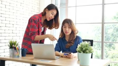 İki arkadaş internetten alışveriş yapıyor. İnternet sitesinde bilgisayardan alışveriş yapıyor. Gülümseyen yüzlü, mutlu. İnternetten bilgisayar alışverişi yapan mutlu Asyalı kadınlar, yeni konsept ödeme