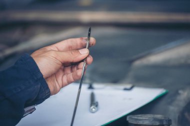 Araba tamircisi, servis alanında motor yağı mekaniğini elle kontrol ediyor. El kapatma adam motor yağı seviyesini kontrol et. Dipstick 'i bul, temizle, motor yağı doldurmadan önce dipstick seviyesini kontrol et.