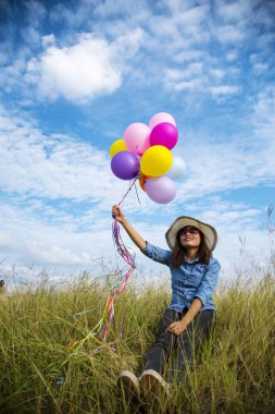 Yeşil çayır bulutu üzerinde koşan balonları tutan bir kadın. Mavi gökyüzü. Mutluluk dolu ve rahatlatıcı. Hava balonları tutan eller doğum günü partisinde oynar Mutlu zamanlar yaz güneşi açık havada
