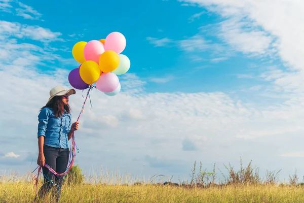 女人拿着气球在绿色的草地上跑着 白云和蓝天快乐而轻松 手握着生气勃勃的气球在生日派对上玩耍快乐的夏天户外阳光 — 图库照片