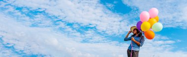 Yeşil çayır, beyaz bulut ve mavi gökyüzü mutlulukla dolup taşan balonlar tutan neşeli sevimli kız. Panorama Eller canlı hava balonları tutuyor Mutlu zamanlar yaz güneşi açık hava fotokopi alanı