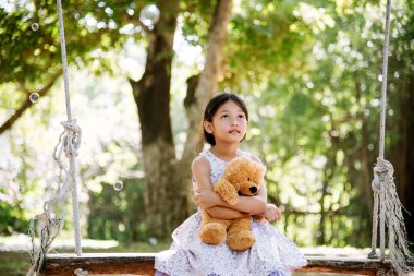 Yeşil Park 'ta oyuncak ayıya sarılırken mutlu çocuk. Oyuncak ayı, küçük çocuklar için en iyi arkadaş tatlı kız. Otizm mutlu bir şekilde oyun bahçesinde birlikte oynayarak mutlu bir aile sevgisi ve sıcacık kucaklaşmayı hisseder.