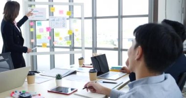 Mutlu iş adamları toplantı odasında grafik çizelgesi yatırımıyla ve iş verileriyle tanışıyor. Bir grup iş adamı konferans odasında toplanıyor. Asyalı iş adamı konuşması, mevcut takım çalışması ortaklığı