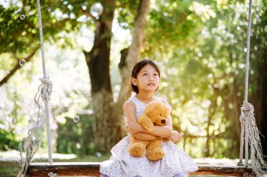 Yeşil Park 'ta oyuncak ayıya sarılırken mutlu çocuk. Oyuncak ayı, küçük çocuklar için en iyi arkadaş tatlı kız. Otizm mutlu bir şekilde oyun bahçesinde birlikte oynayarak mutlu bir aile sevgisi ve sıcacık kucaklaşmayı hisseder.