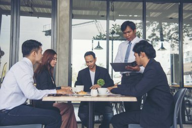 Bir grup iş adamı konferans odasında toplantı yapıyor. İşletme doküman grafiği ofis masasına danışmak için beyin fırtınası yapıyorlar. Çeşitli etnik gruplardan iş adamları beyin fırtınası yapıyor ve birlikte çalışıyorlar..