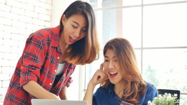 Asyalı iş arkadaşı arkadaşlığı, gülen yüzle. Mutluluk iki kadın meslektaşın ofis masasında takım çalışması. Bilgisayar şirketi ile çalışan takım ortakları