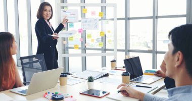 Mutlu iş adamları toplantı odasında grafik çizelgesi yatırımıyla ve iş verileriyle tanışıyor. Bir grup iş adamı konferans odasında toplanıyor. Asyalı iş adamı konuşması, mevcut takım çalışması ortaklığı