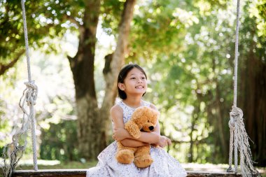 Yeşil Park 'ta oyuncak ayıya sarılırken mutlu çocuk. Oyuncak ayı, küçük çocuklar için en iyi arkadaş tatlı kız. Otizm mutlu bir şekilde oyun bahçesinde birlikte oynayarak mutlu bir aile sevgisi ve sıcacık kucaklaşmayı hisseder.